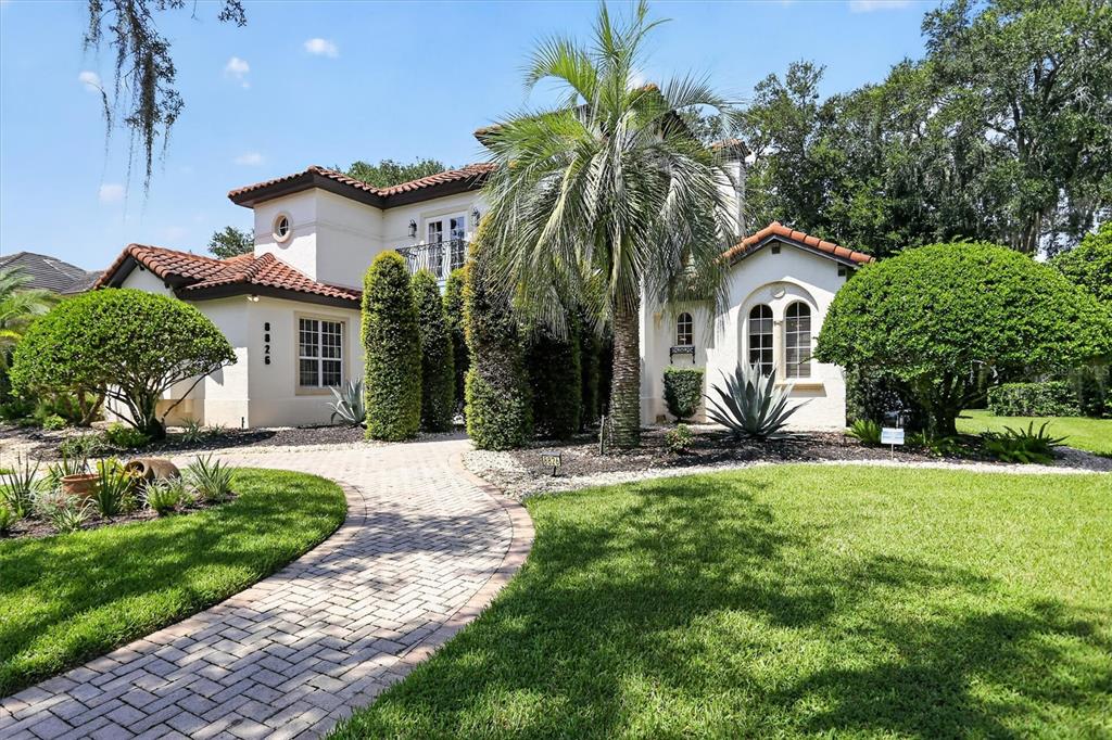 A two-story stucco house with a tile roof, palm tree, and brick walkway — 8826 SOUTHERN BREEZE DRIVE, ORLANDO, FL