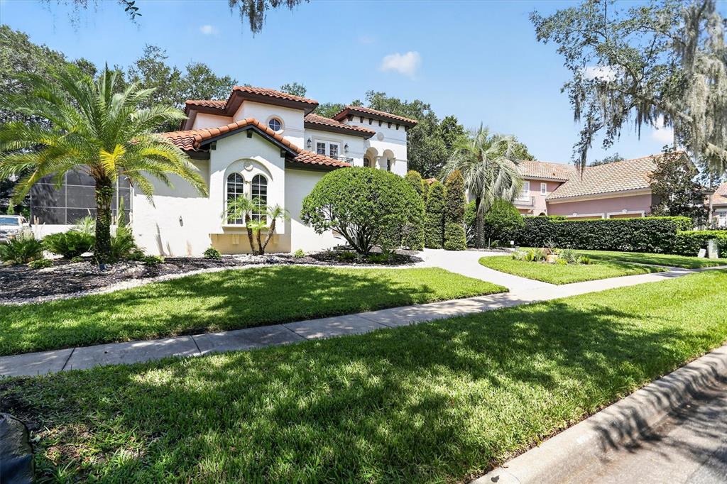 A two-story stucco house with a tile roof, palm trees, and a manicured front lawn — 8826 SOUTHERN BREEZE DRIVE, ORLANDO, FL