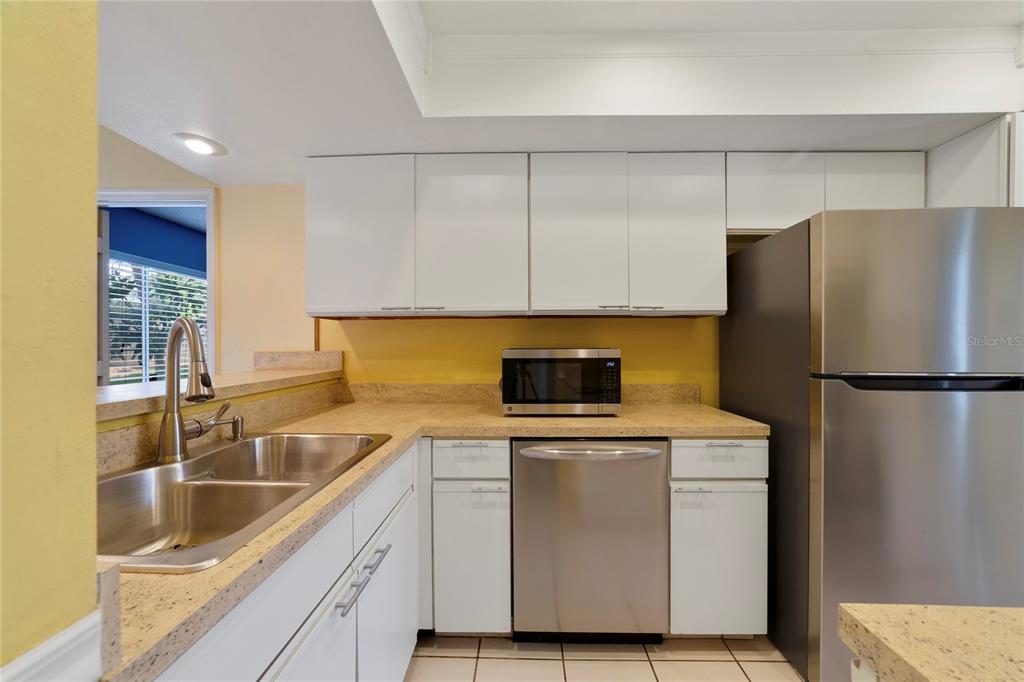 A kitchen features white cabinets, stainless steel appliances, and tan speckled countertops — 260 W SABAL PALM PLACE, LONGWOOD, FL