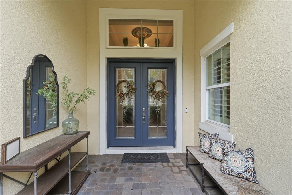 A covered entryway features a blue double door, a wooden console table, and a bench — 125 ASTERBROOKE DRIVE, DELAND, FL