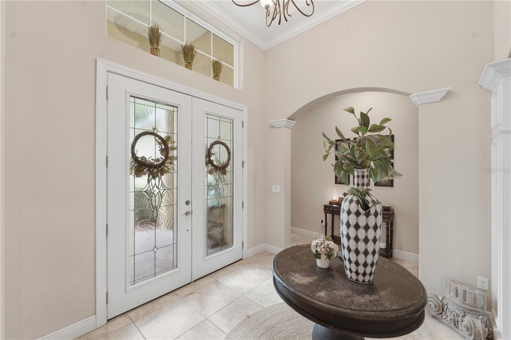 A bright foyer features a double front door, tile flooring, and a central pedestal table — 125 ASTERBROOKE DRIVE, DELAND, FL