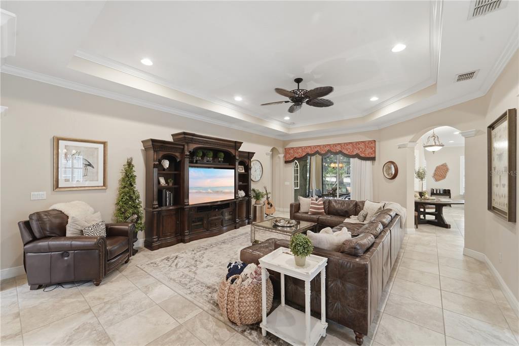 A living room features a large entertainment center, leather furniture, and a tray ceiling — 125 ASTERBROOKE DRIVE, DELAND, FL