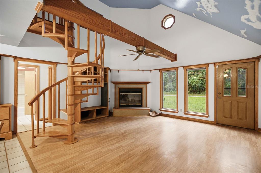 A living room features a wooden spiral staircase, a fireplace, and a vaulted ceiling — 3580 NE 160TH LANE, CITRA, FL