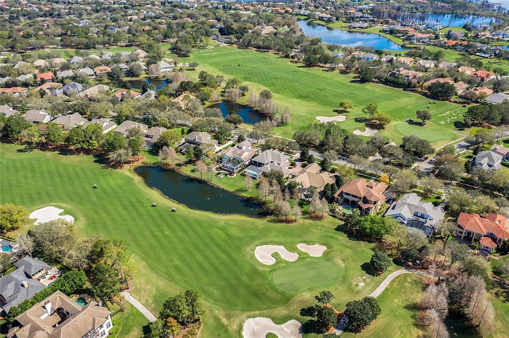 An aerial view shows houses bordering a golf course with several ponds and sand traps — 11524 CLAYMONT CIRCLE, WINDERMERE, FL