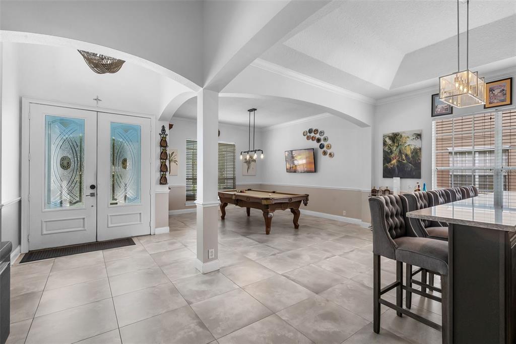 A spacious room features tile flooring, a pool table, and a kitchen island with bar stools — 11524 CLAYMONT CIRCLE, WINDERMERE, FL