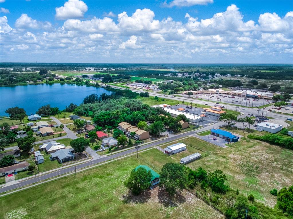 An aerial view shows a residential neighborhood, a lake, and a commercial shopping center nearby — 1001 S LAKE ANOKA BOULEVARD, AVON PARK, FL