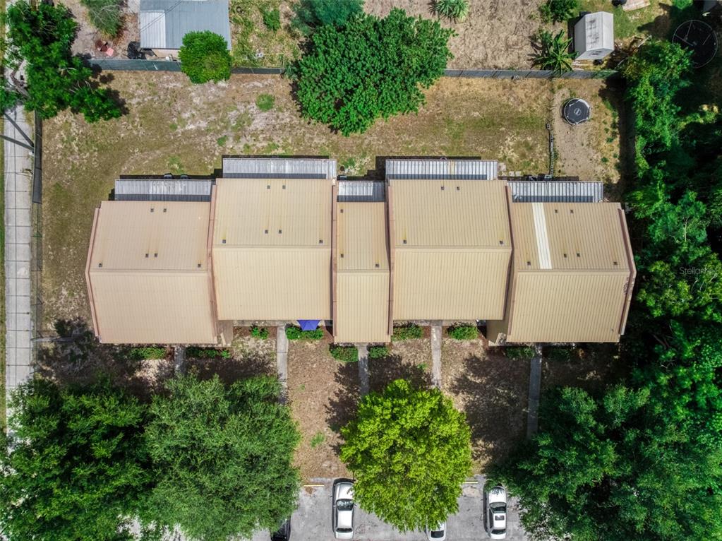 An aerial view shows a multi-unit residential building with metal roofs and surrounding green space — 1001 S LAKE ANOKA BOULEVARD, AVON PARK, FL