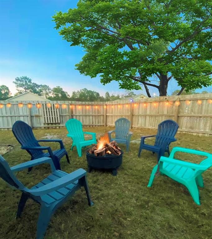 A backyard features a fire pit surrounded by five plastic chairs in front of a fence — 2129 N PINE CONE AVENUE, LECANTO, FL