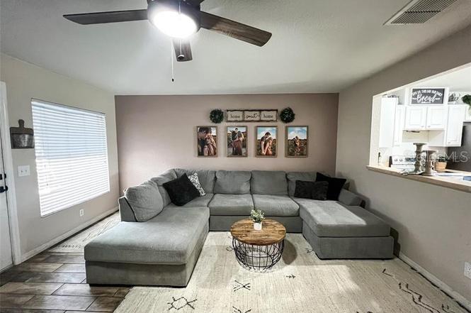 A living room features a large gray sectional sofa, a round coffee table, and wall art — 2129 N PINE CONE AVENUE, LECANTO, FL