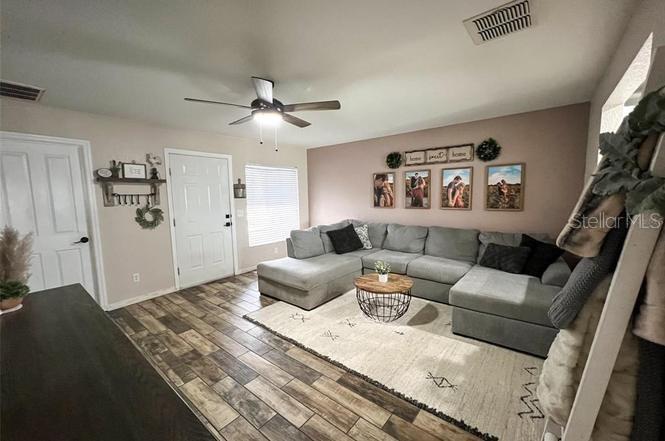 A living room features a gray sectional sofa, a wooden coffee table, and wood-look flooring — 2129 N PINE CONE AVENUE, LECANTO, FL