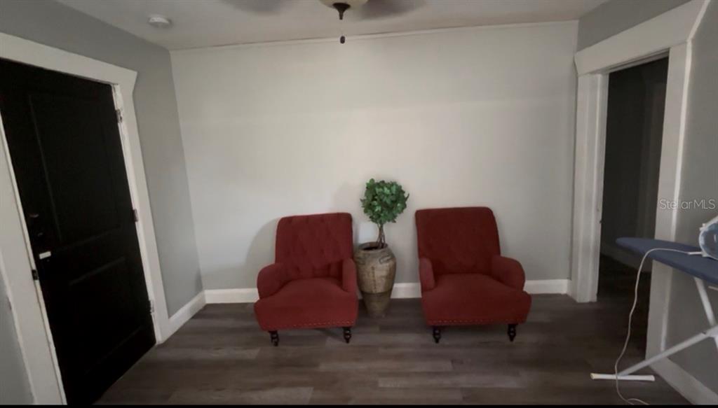 A room with gray walls, wood-look flooring, two red armchairs, and a potted plant — 611 N LINCOLN AVENUE, LAKELAND, FL