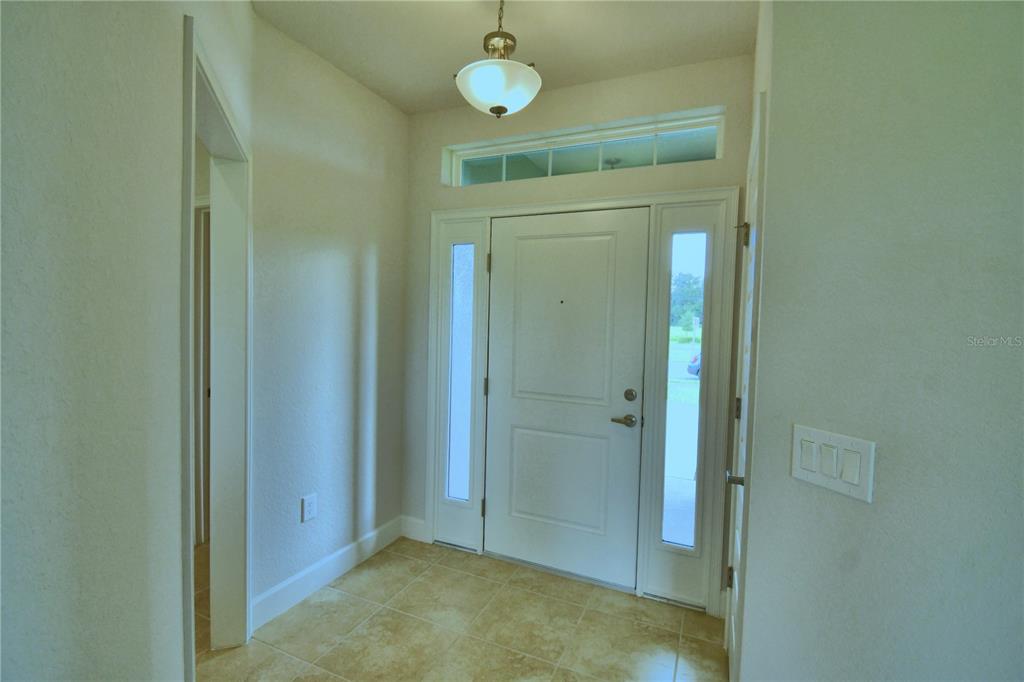An entryway features tile flooring, a white front door with sidelights, and a ceiling light — 4628 CALAMINT LANE, AUBURNDALE, FL