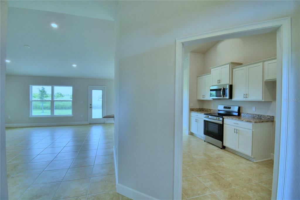 A view through a doorway into a kitchen with white cabinets and stainless appliances — 4628 CALAMINT LANE, AUBURNDALE, FL