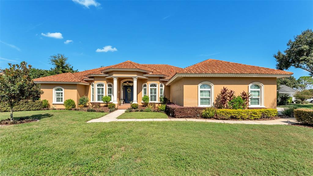 A tan single-story house with a terracotta tile roof and a front lawn — 237 MCLEAN POINT, WINTER HAVEN, FL
