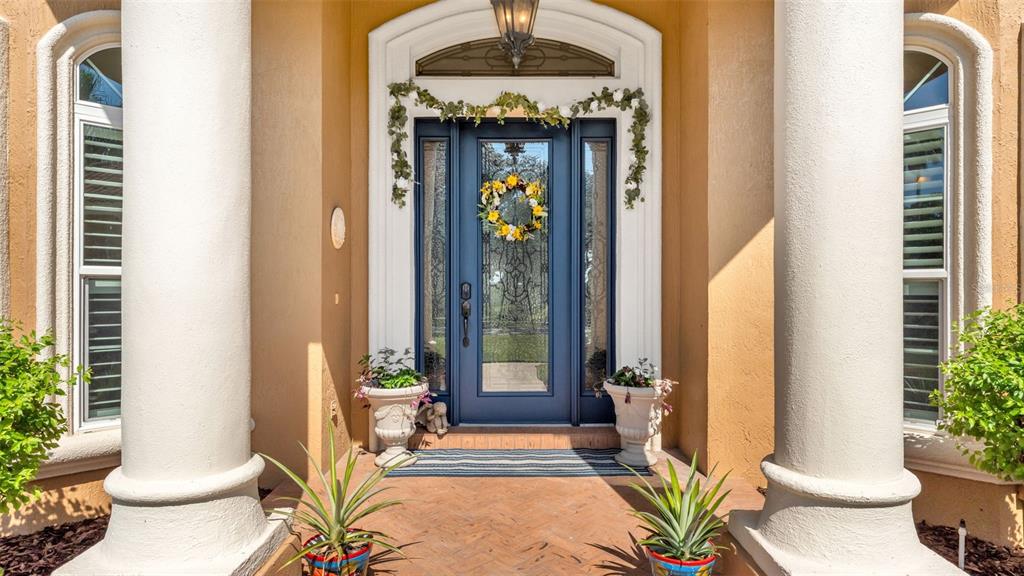 A blue front door with a glass insert is framed by two large white columns — 237 MCLEAN POINT, WINTER HAVEN, FL
