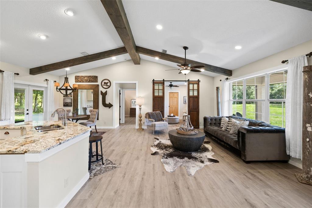 A living room with vaulted ceilings, exposed wood beams, and a dark velvet sofa — 14765 US HIGHWAY 41, SPRING HILL, FL