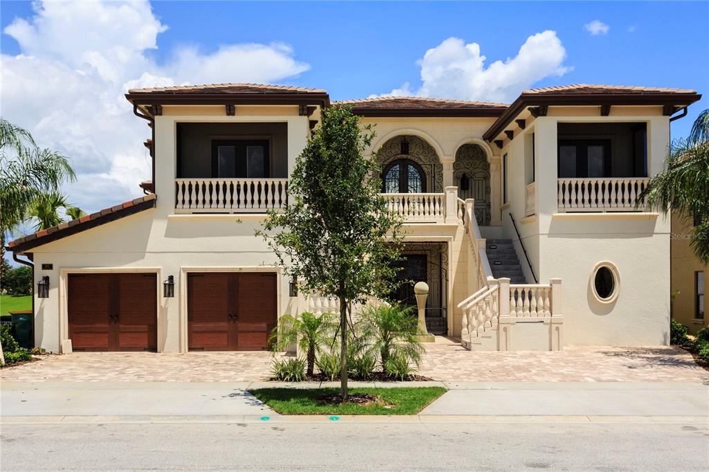 A two-story Mediterranean-style house with a stucco exterior, two garages, and an elevated front entrance — 905 GOLDEN BEAR DRIVE, REUNION, FL