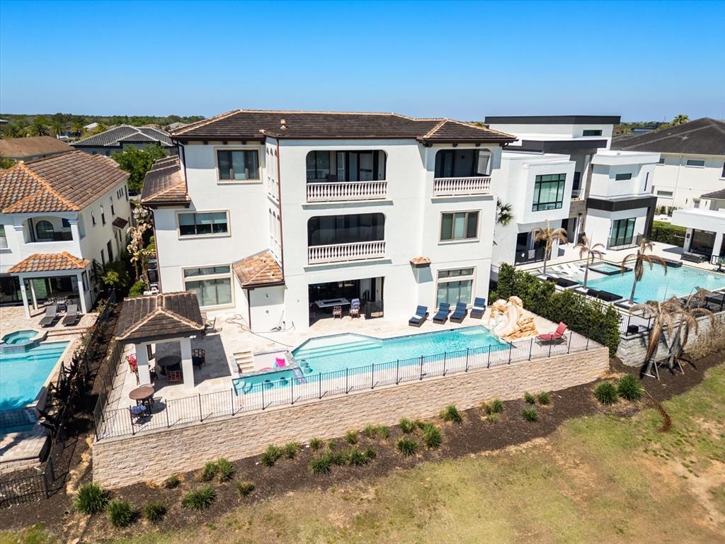 An aerial view of a three-story white house with a pool and patio area — 905 GOLDEN BEAR DRIVE, REUNION, FL