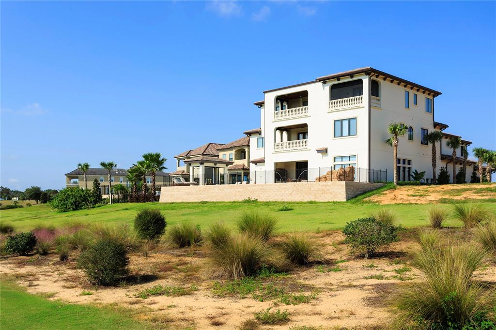 A large, multi-story Mediterranean-style house sits on a grassy hill under a clear blue sky — 905 GOLDEN BEAR DRIVE, REUNION, FL