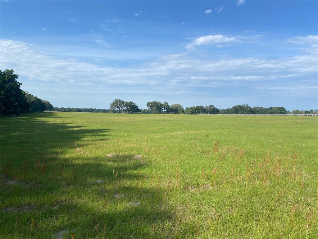 A vast, flat, grassy field under a bright blue sky with scattered clouds — 0 NW 163 TERRACE, MORRISTON, FL