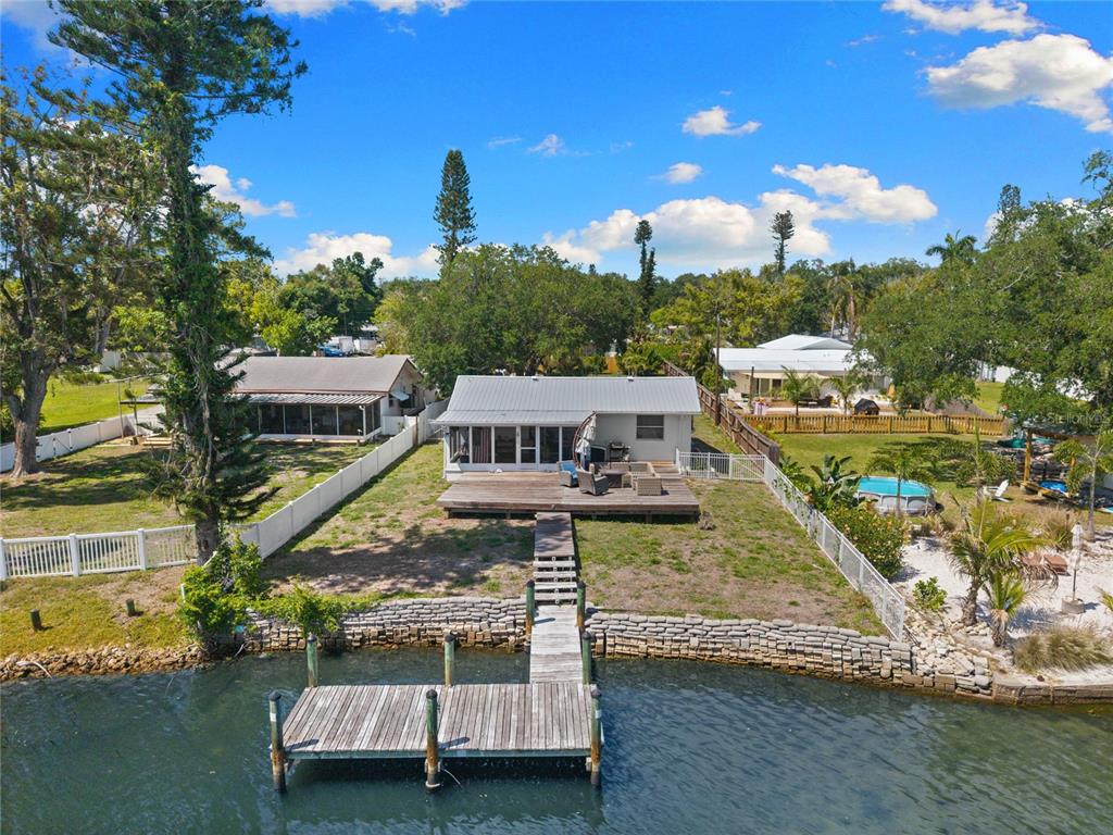 An aerial view of a waterfront house with a wooden deck and a private dock — 704 69TH AVENUE W, BRADENTON, FL