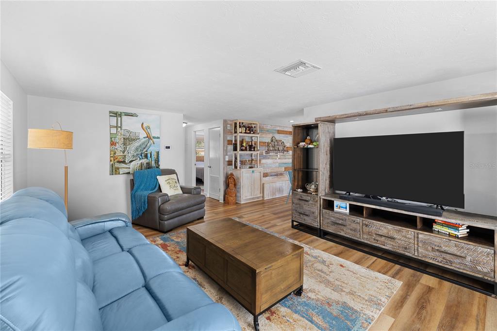 A living room features a blue leather sofa, a wooden coffee table, and a television console — 704 69TH AVENUE W, BRADENTON, FL
