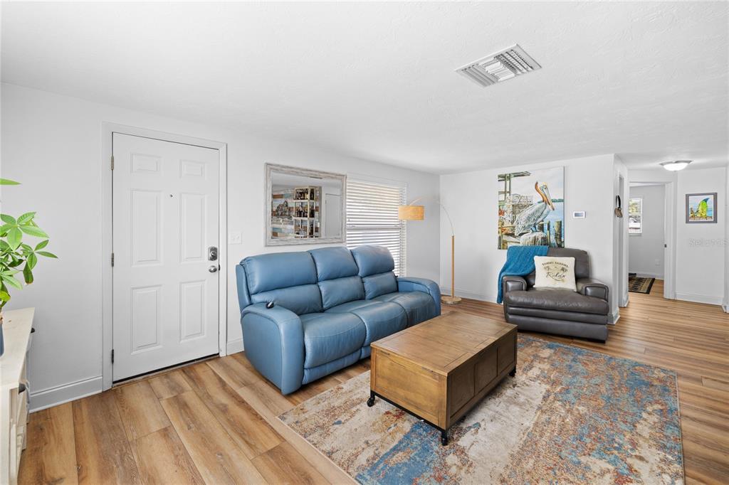 A living room features a blue sofa, a wooden coffee table, and wood-look flooring — 704 69TH AVENUE W, BRADENTON, FL