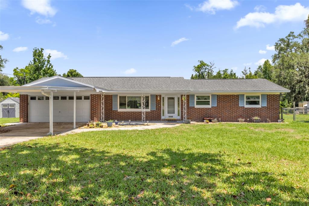 A single-story brick house with a carport, a front lawn, and a light-colored roof — 35505 CRESCENT DRIVE, FRUITLAND PARK, FL