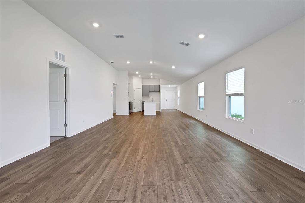 An open-concept living area features white walls, recessed lighting, and wood-look flooring — 5704 LAGOON CRUISE WAY, JACKSONVILLE, FL