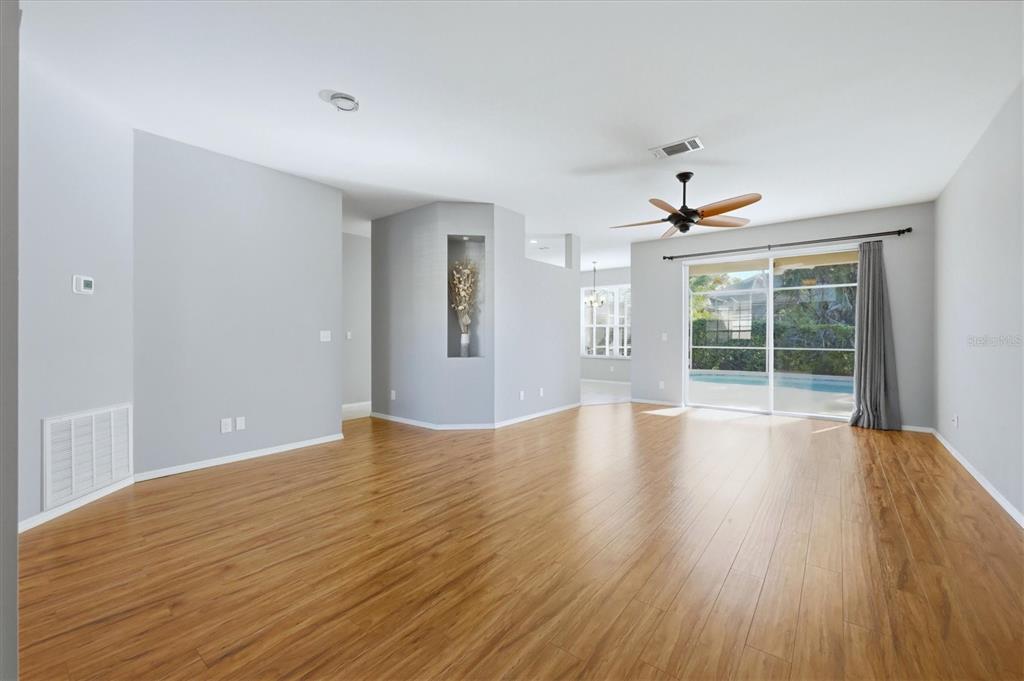A living room features light gray walls, wood-look flooring, a ceiling fan, and sliding glass doors — 5009 46TH STREET W, BRADENTON, FL