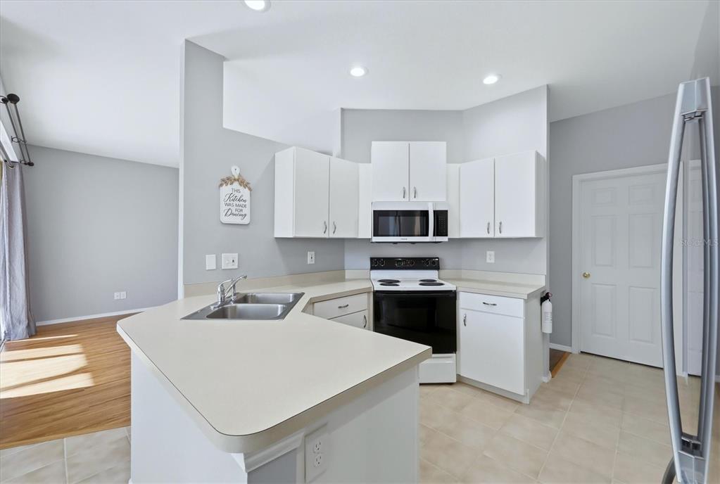 A kitchen features white cabinets, a black stove, a microwave, and a light-colored countertop — 5009 46TH STREET W, BRADENTON, FL