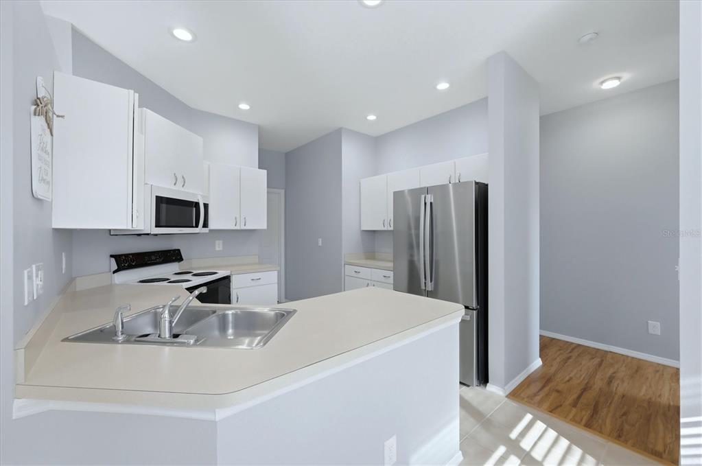 A kitchen features white cabinets, stainless steel appliances, a double sink, and light-colored countertops — 5009 46TH STREET W, BRADENTON, FL