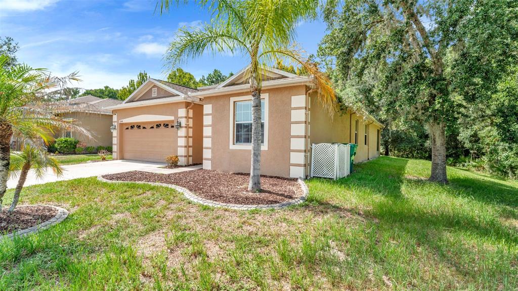 A tan stucco house with a two-car garage and a palm tree in the front yard — 12848 WHITE BLUFF ROAD, HUDSON, FL