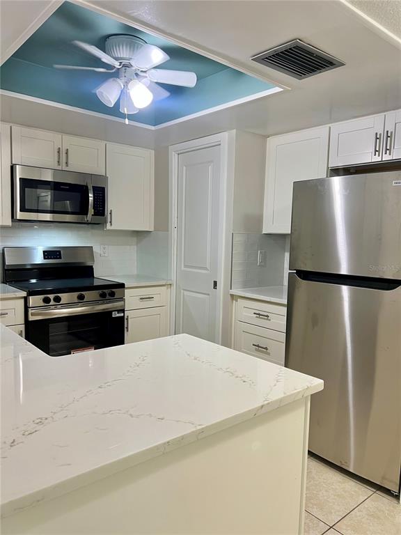 A kitchen features white cabinets, stainless steel appliances, a quartz countertop, and a blue ceiling — 632 EDGEWATER DRIVE UNIT 139, DUNEDIN, FL