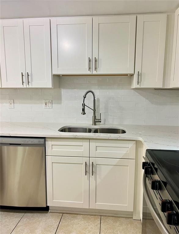 A kitchen features white shaker cabinets, a stainless steel sink, and a white subway tile backsplash — 632 EDGEWATER DRIVE UNIT 139, DUNEDIN, FL