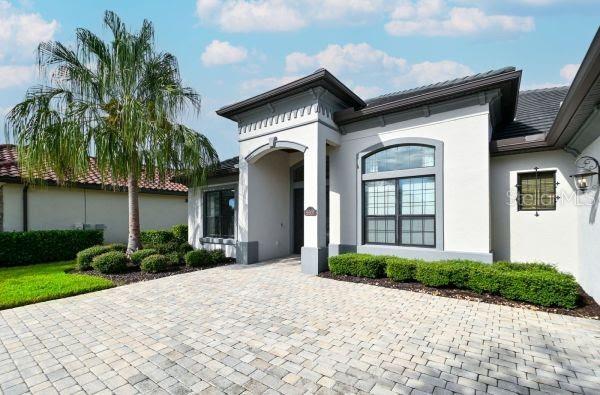 A paved driveway leads to the front entrance of a single-story stucco house with landscaping — 5507 ARNIE LOOP, LAKEWOOD RANCH, FL