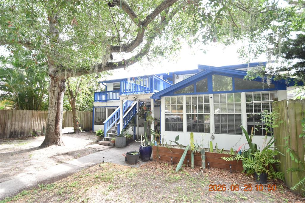 A two-story house with a blue-trimmed sunroom, an exterior staircase, and a large shade tree — 2926 51ST STREET S UNIT 3, GULFPORT, FL