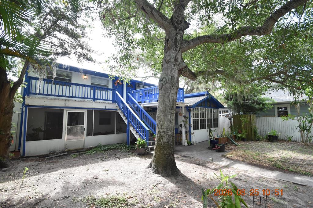 A two-story house with a blue-railed deck and staircase sits behind a large tree — 2926 51ST STREET S UNIT 3, GULFPORT, FL