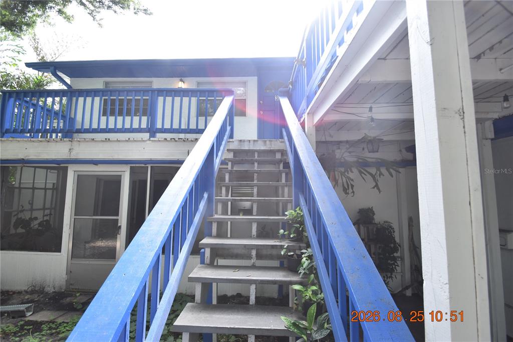 An exterior view shows a wooden staircase leading to a second-story balcony with blue railings — 2926 51ST STREET S UNIT 3, GULFPORT, FL