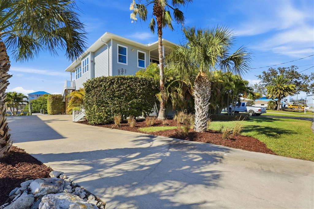 A light blue two-story house with a concrete driveway and palm trees in the yard — 13875 HATCHER AVENUE, HUDSON, FL