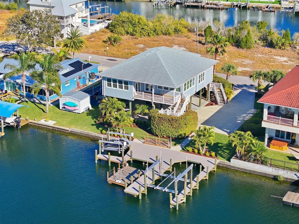 An aerial view shows a stilt house with a private dock on a canal — 13875 HATCHER AVENUE, HUDSON, FL