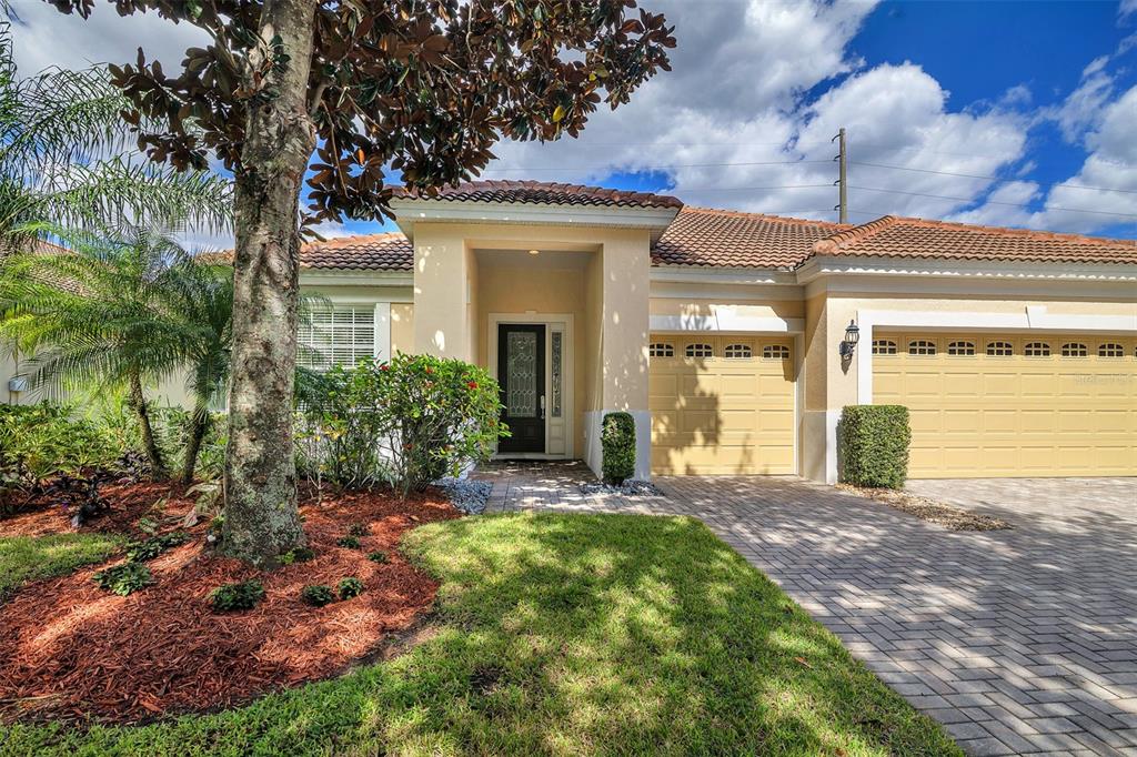 A single-story house with a beige stucco exterior, a tiled roof, and a paved driveway — 524 DOUGLAS EDWARD DRIVE, OCOEE, FL