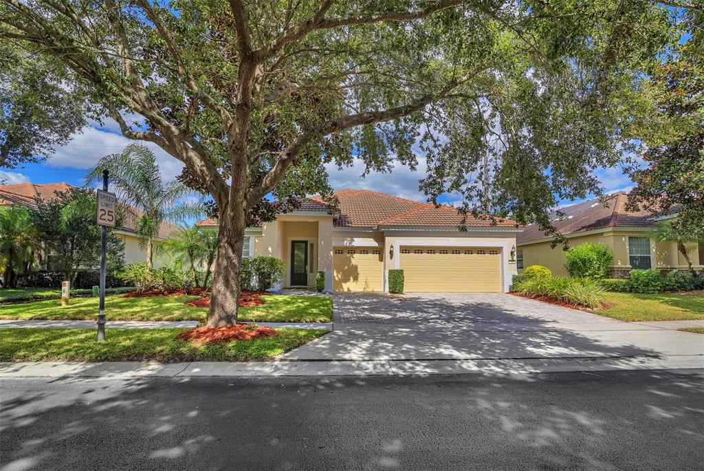 A single-story house with a tile roof, three-car garage, and a large tree in front — 524 DOUGLAS EDWARD DRIVE, OCOEE, FL