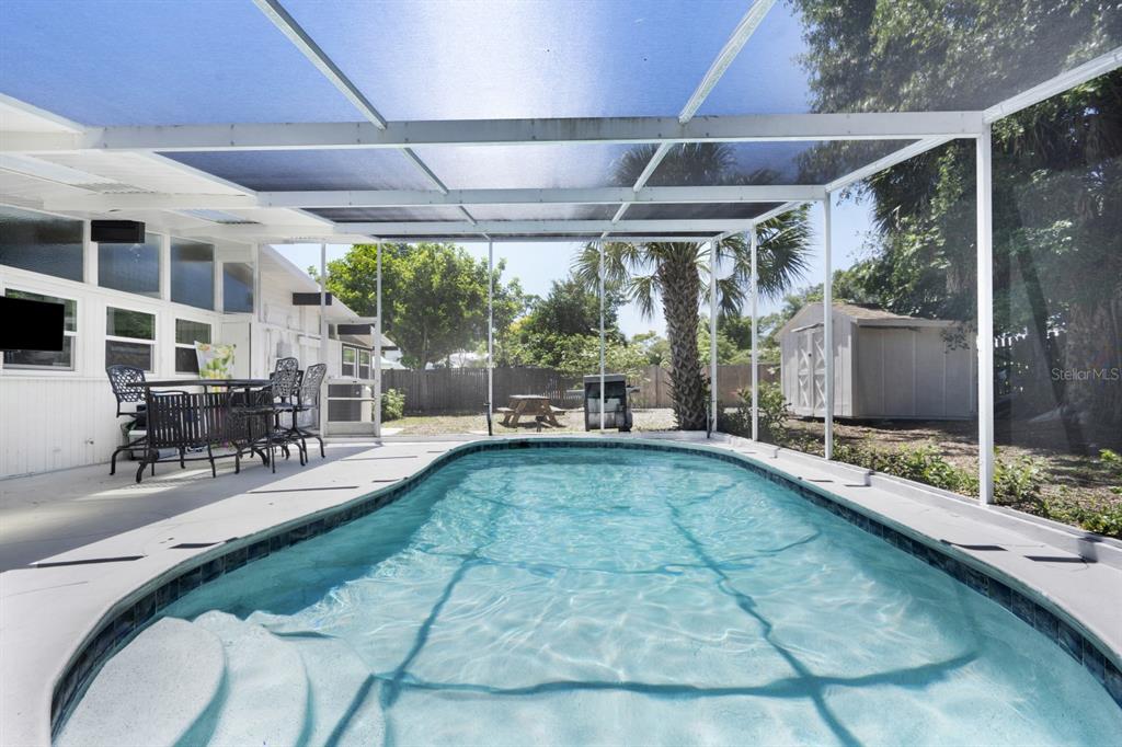 A swimming pool is enclosed by a screened lanai with a patio and outdoor furniture — 2213 WASON ROAD UNIT 2, SARASOTA, FL