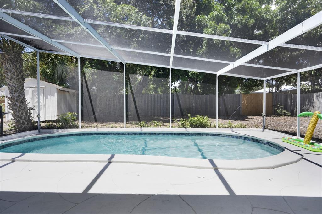 A swimming pool with a screen enclosure sits in a backyard with a storage shed — 2213 WASON ROAD UNIT 2, SARASOTA, FL