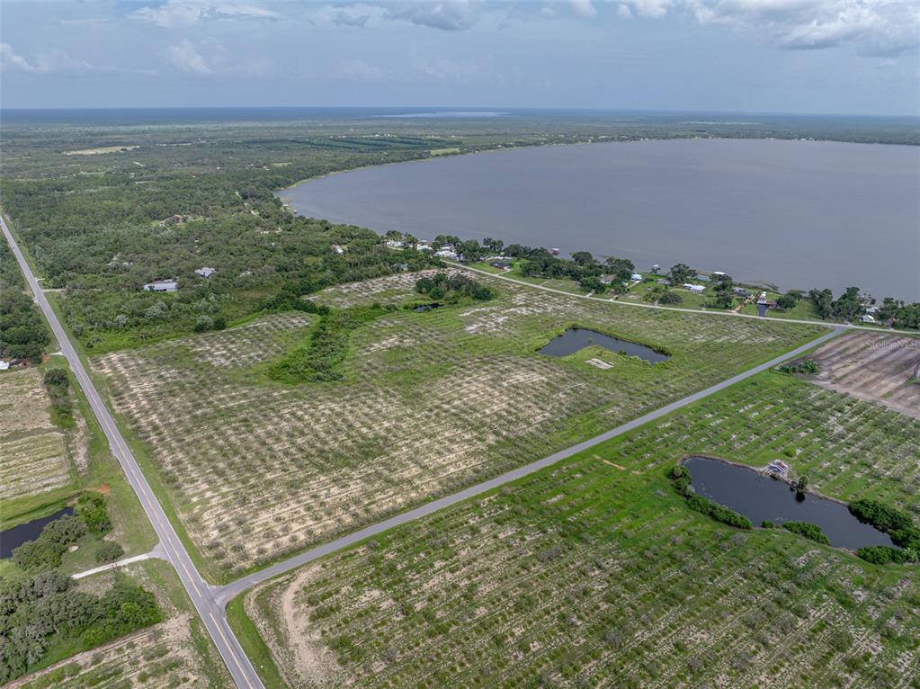 An aerial view shows a large, grassy plot of land adjacent to a lake — 0 LAKE REEDY BOULEVARD, FROSTPROOF, FL