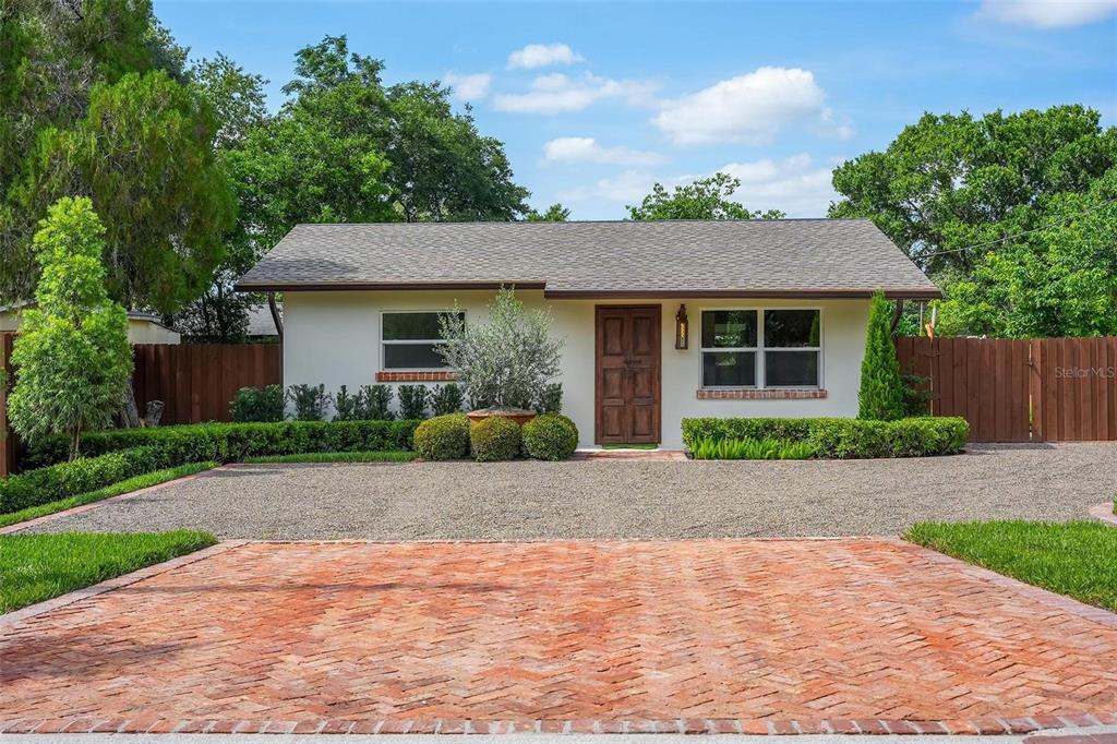 A single-story house with a brick driveway, gravel parking area, and a wooden front door — 10541 3RD AVENUE, OCOEE, FL