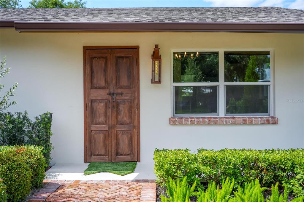 A front exterior view shows a wooden double door, a window, and a brick walkway — 10541 3RD AVENUE, OCOEE, FL