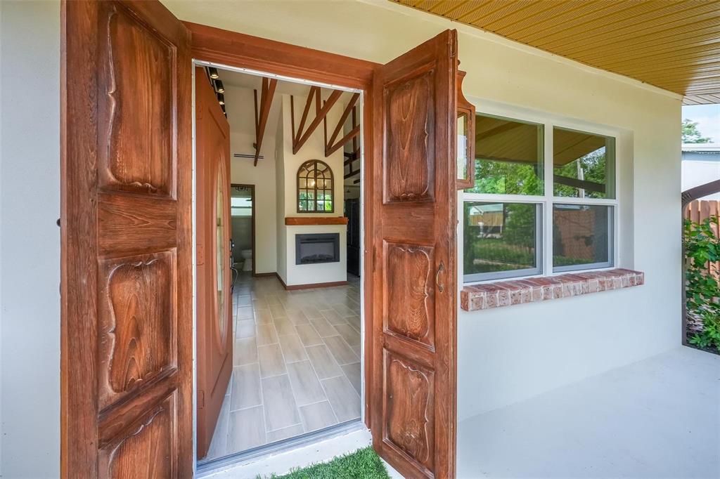 An open wooden front door reveals a tiled entryway with a view into the home — 10541 3RD AVENUE, OCOEE, FL