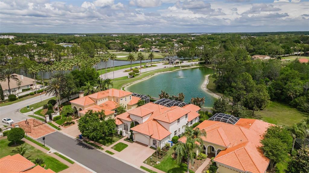 An aerial view shows several houses with orange tile roofs near a pond and trees — 1246 TUSCANY DRIVE, TRINITY, FL